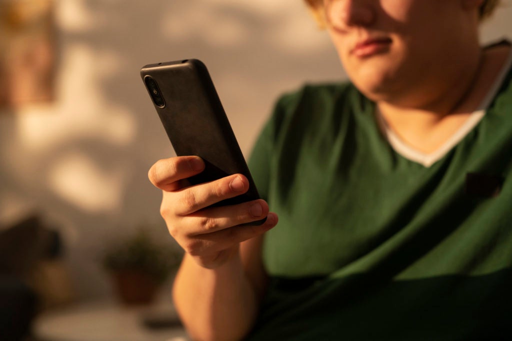 Pessoa segurando um smartphone ao ar livre, simbolizando a proteção do seguro de celular.